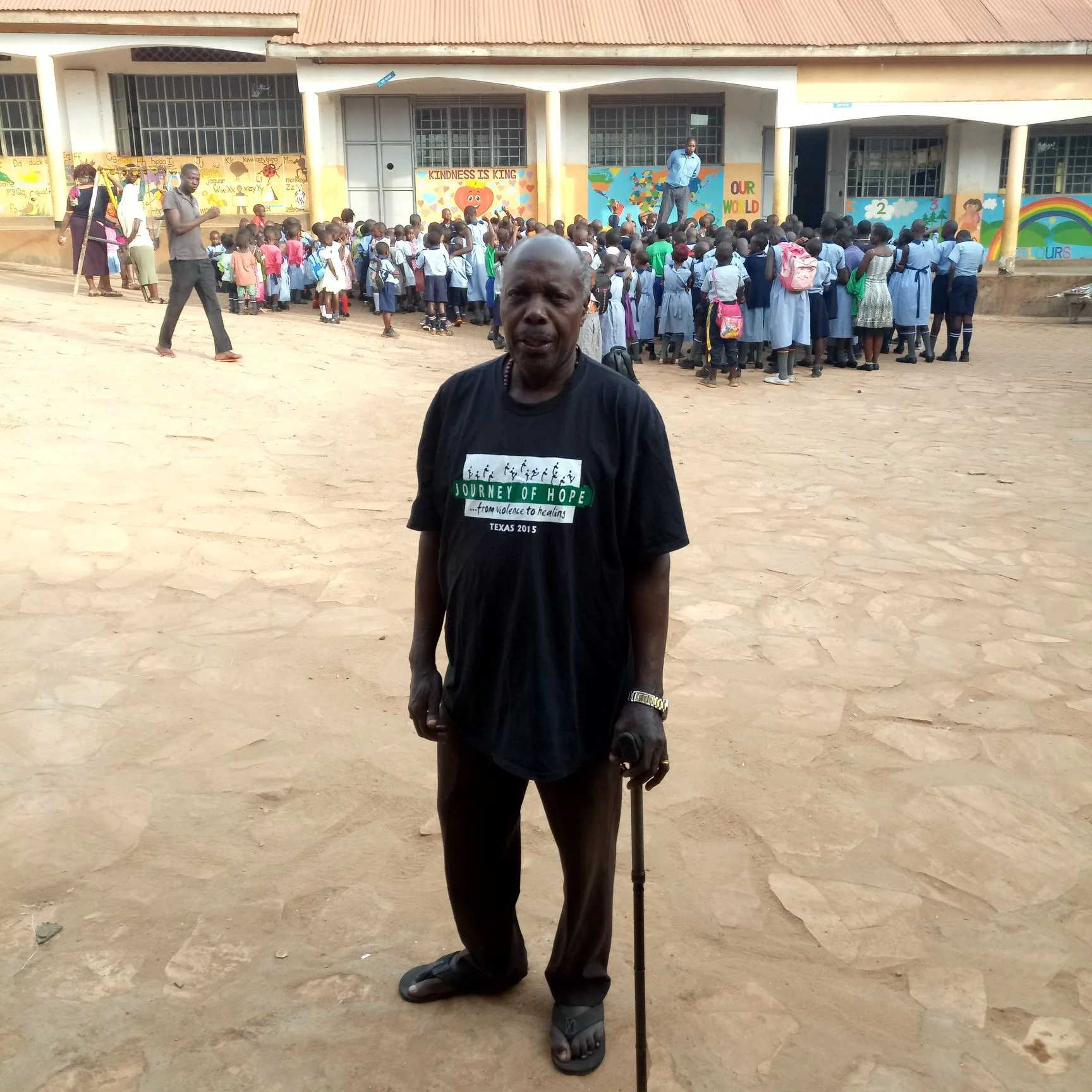 Edward standing in front of the school with students gathering behind him