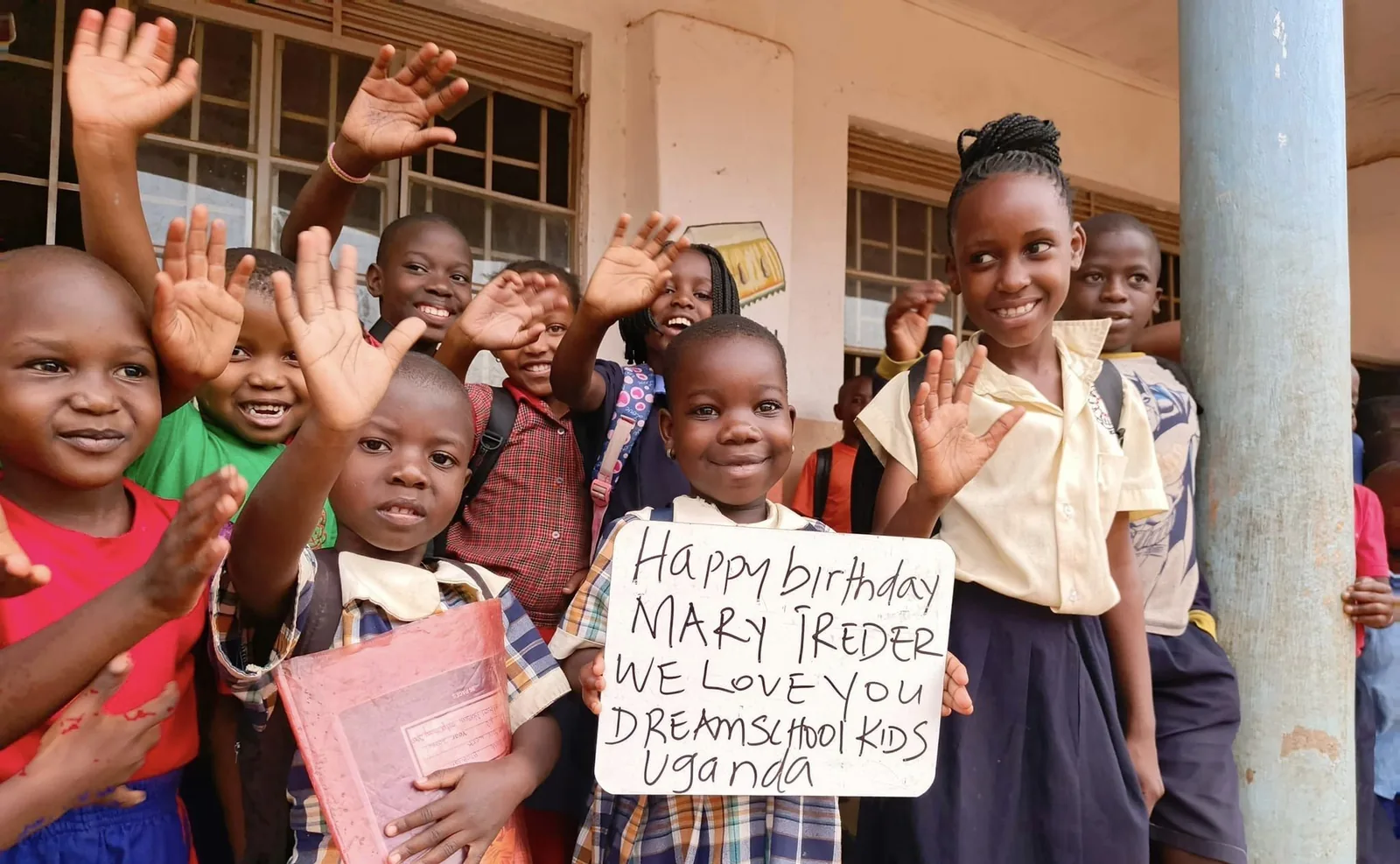 Schoolchildren waving and holding a handwritten birthday greeting